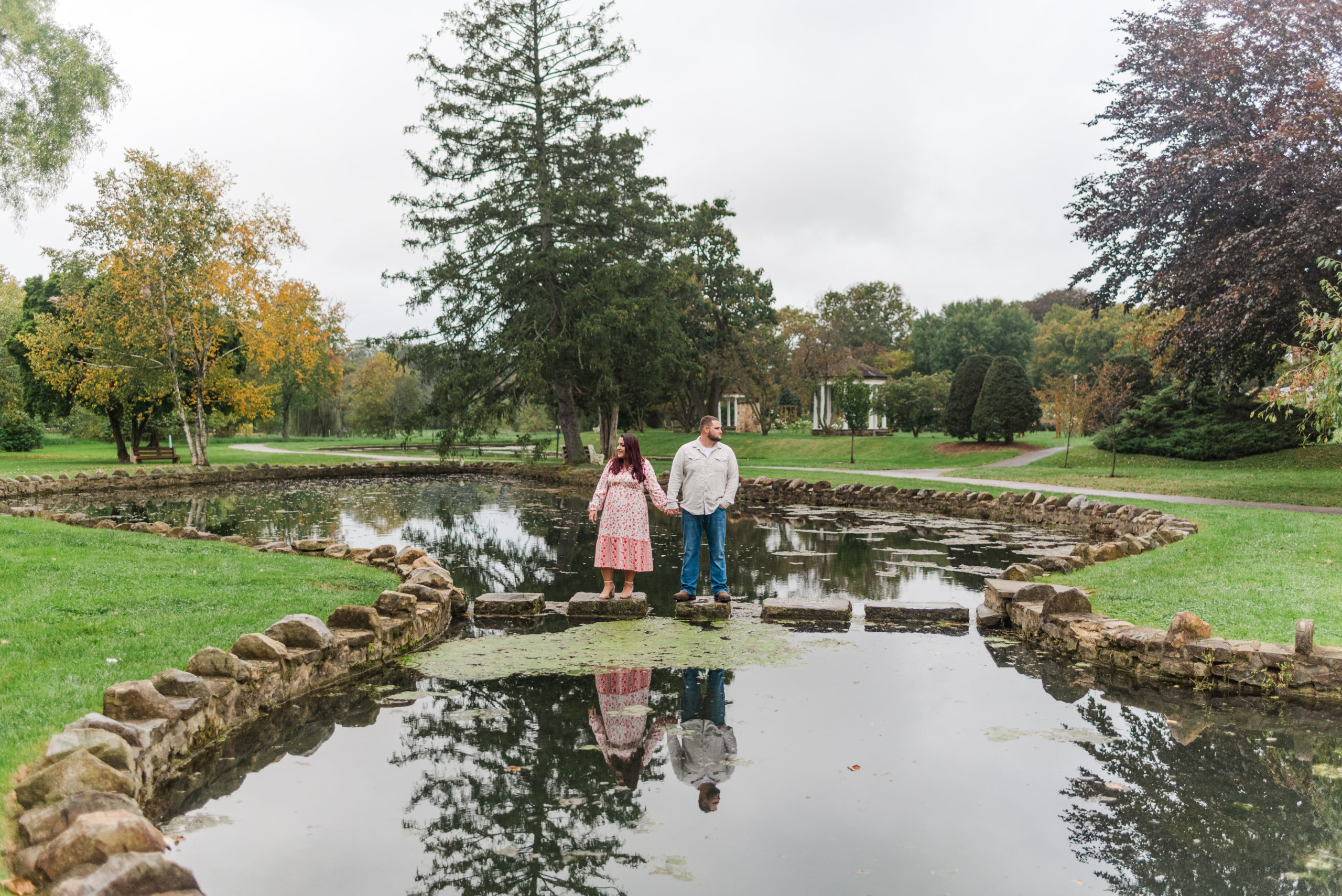 Couple standing by pond stare in opposite directions