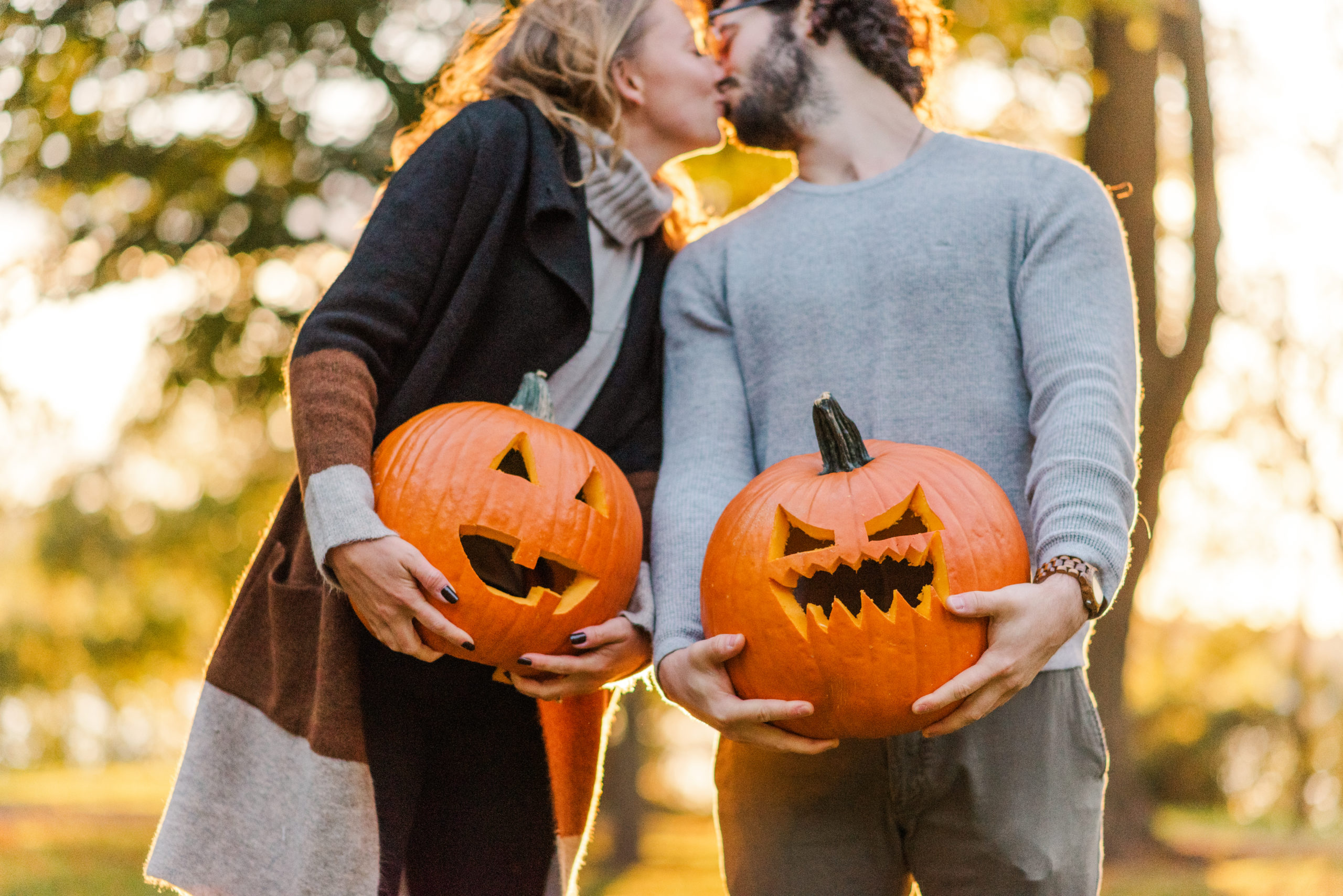 Couple holding jack-o-lanterns kiss